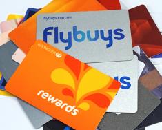 Top-down view of a stack of loyalty cards, including Coles Flybuys and Woolworths Rewards