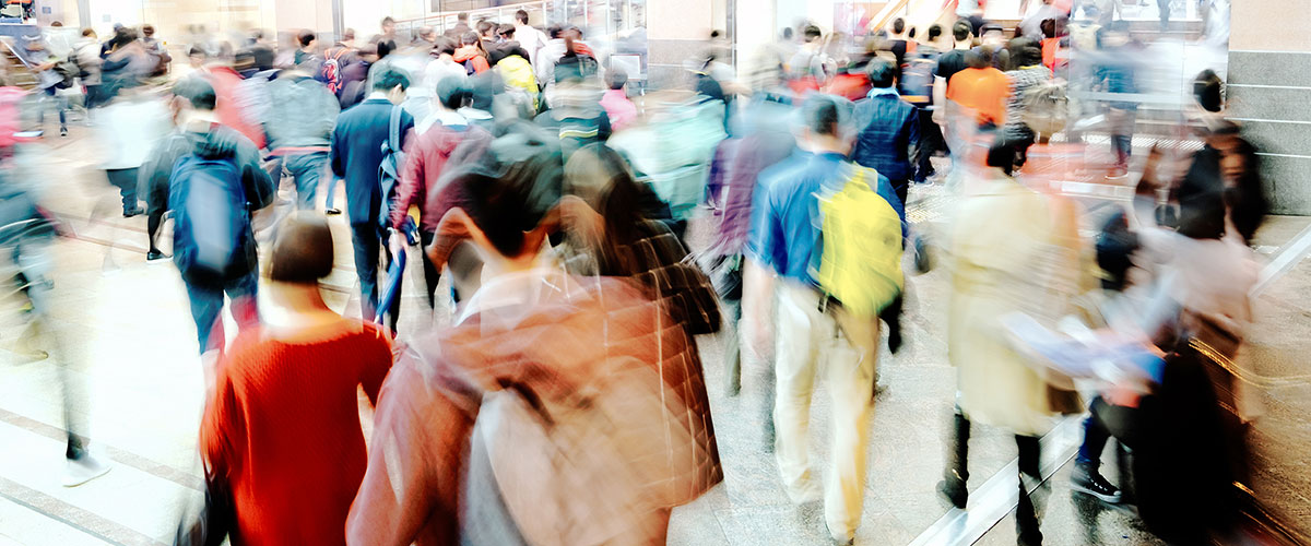 Blurred people walking through a city environment on a pedestrian crossing