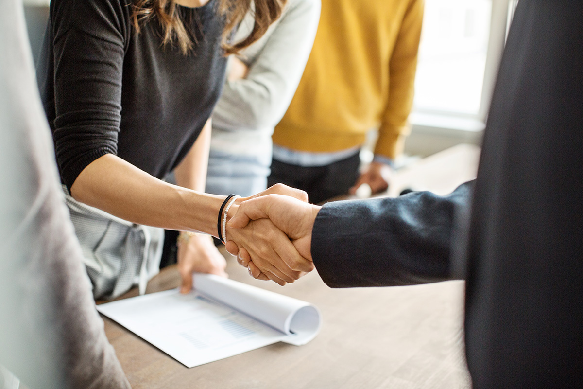 Close up of two people in black suits shaking hands 