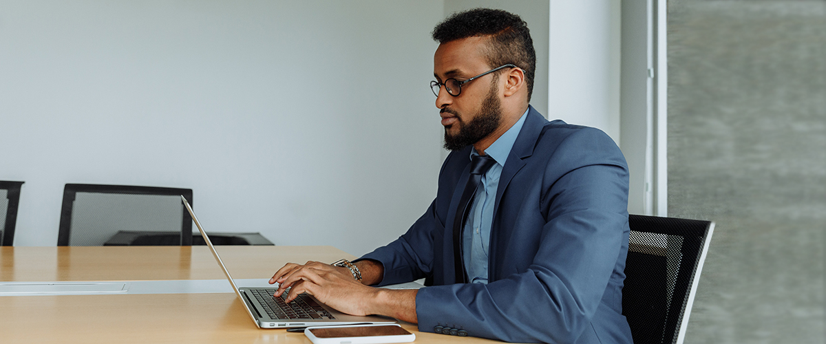 Photo of man in suit looking at his laptop in an office environment