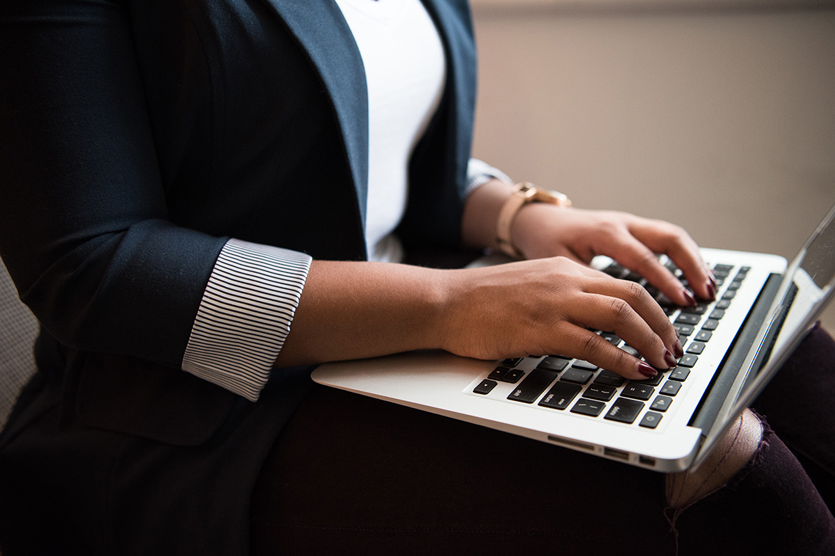 Close up photograph of a person typing on their laptop